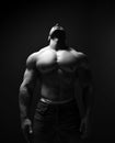 Black and white portrait of tall muscular man, athlete with perfect built body standing shirtless with head thrown back