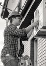 Black and white portrait of smiling techician repairing air conditioning system