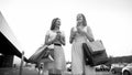 Black and white portrait of two girls with shoppings bags on car parking after doing shopping in mall Royalty Free Stock Photo