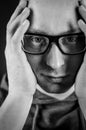 Black and white portrait of a young bald man with black eyeglasses holding his head in his hands Royalty Free Stock Photo