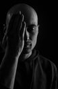 Black and white portrait of a young bald man who covers the middle of his face with his hand and keeps his eyes closed Royalty Free Stock Photo