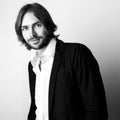 Black-white portrait of young handsome long hair man against studio background