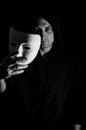 Black and white portrait of a young hooded man taking off his mask, concept for being true and authentic Royalty Free Stock Photo