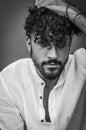 Black and white portrait of a young man with beard and curly hair, who with a hand on his head in his hair looks worried Royalty Free Stock Photo