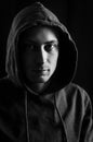 Black and white portrait of a young man with a hood covering his head who in the shadow has a serious and determined look Royalty Free Stock Photo