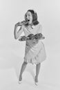 Black and white portrait of young redhead woman in cute pink dress biting freshly baked buns. Vintage, retro style Royalty Free Stock Photo