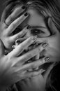 Black and white portrait of a young woman with her face covered with hands, concept for showing the anxieties and fears of women