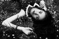 Black and white portrait of young woman lying on grass with small flowers. Top view Royalty Free Stock Photo