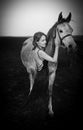 Black and white portrtait of beautiful woman in evening dress posing next to horse. Royalty Free Stock Photo