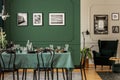 Black and white posters on wall of stylish dining room interior with log table with wine glasses, plates and cones Royalty Free Stock Photo