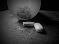 Black and white prescription pills drugs spilling on wooden table