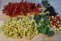 Black, white and red currants lie next to strawberries and leaves on a wooden table. Royalty Free Stock Photo