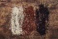Black, white and red quinoa in spoons, raw quinoa groats assorted, wooden rustic kitchen table, top view Royalty Free Stock Photo