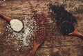 Black, white and red quinoa in spoons, raw quinoa groats assorted, wooden rustic kitchen table, top view Royalty Free Stock Photo