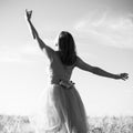 Black and white romantic beautiful young lady having fun standing in the field with hand up to the sky on outdoors background