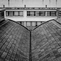 Black and white the roof of the building looks like an open book on the background of another industrial building