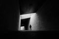Black and white scene of lone man walking through tunnel