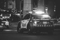 Black and white shot of the backend of a Toronto Police Service with emergency lights activated