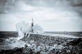 Black and white shot of Imogen Storm with large waves crashing against the harbor wall