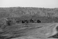 Black and white shot of riders on horses in a desolated rocky area