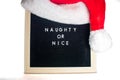 A Sign That Says Naughty or Nice With A Christmas Hat On Top