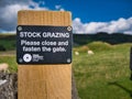 A black and white sign fixed to a wooden post advises that farm stock are grazing in the field ahead.