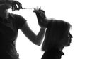 Black and white silhouette hairdresser cuts client's hair