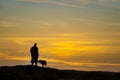 Black and white silhouette of man and his dog on top of hill at sunset -  room for text copy Royalty Free Stock Photo