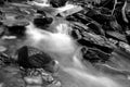 Black and White Slow Shutter Speed Photography of a Small River with Moss Covered Rocks in the Woods. Royalty Free Stock Photo