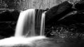 Black and White Slow Shutter Waterscape Photography of a Waterfall with Mossy Stones in the Woods. Royalty Free Stock Photo