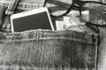 black and white Smartphone in front jeans pocket with eye glasses and Algeria coin money,