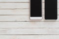 Black and white smartphones with dark screen on wood texture background Royalty Free Stock Photo