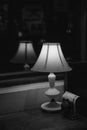 Black and white still life of elegant shiny antique table lamp closeup on dark blurry background. Lamp silhouette blurred reflects