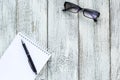 Black and white still life: opened blank notepad, notebooks, pen, glasses.