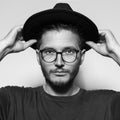 Black and white studio portrait of young handsome man, wearing fedora hat.