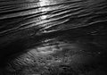 Black and white sunset over calm lake water and beach.