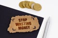 On a black and white surface lies a pen, coins and a cardboard sign with the inscription - Stop wasting money Royalty Free Stock Photo