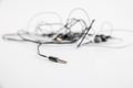 Black and white tangled little headphones lie on a white isolated background. Horizontal frame