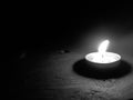 Black and white tealight on dark wood table with knot