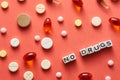 Black and white title NO DRUGS from white cubes on the table with tablets on coral background Royalty Free Stock Photo