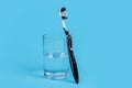 A black and white toothbrush and glass of mouthwash on blue background with copy space Royalty Free Stock Photo