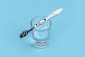 A black and white toothbrush on a glass with mouthwash on blue background with copy space Royalty Free Stock Photo