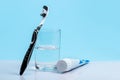 A black and white toothbrush with toothpaste and glass of mouthwash on blue background with copy space Royalty Free Stock Photo