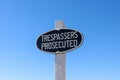 Black and white Trespassers Prosecuted warning sign in a blue