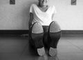 Black and white version of Smiling tap dancer sitting on the dance studio floor in her tap shoes Royalty Free Stock Photo