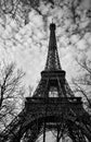 Tall Eiffel Tower rising into cloudy Paris sky, black and white vertical photo Royalty Free Stock Photo