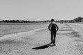 Black & white view of a young man walking on Weymouth beach, Dorset, England.