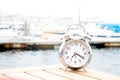 Vintage clock silver put on wood near port with background boat, sea and white sky in morning time, clock concept in holiday time Royalty Free Stock Photo