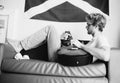 Black and white vintage image style middle shot of young man lying on sofa and playing on guitar in teen room