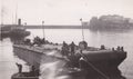 Vintage black and white photo of people on a barge with deep sea diver and welders? 1920s